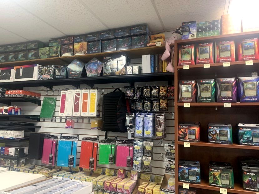 Slatwall and wooden shelving carrying sealed decks, boosters, card sleeves and deck boxes in every colour.